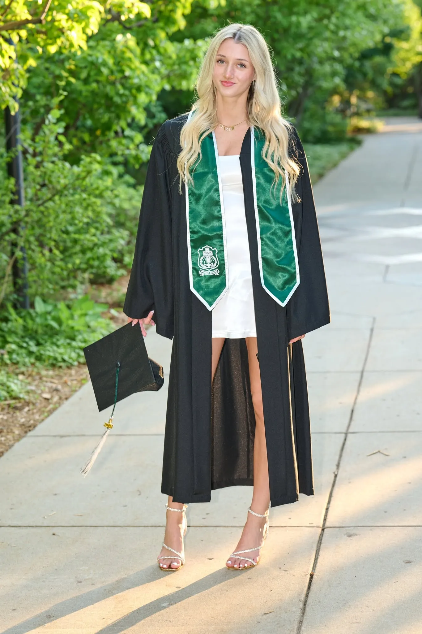 A graduate in cap and gown captured mid stride by a fountain